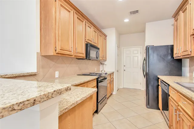 a kitchen with stainless steel appliances granite countertop a refrigerator a stove a sink and a microwave