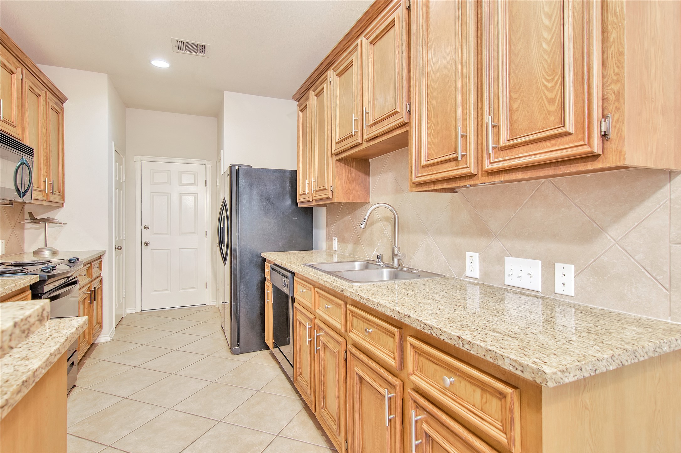 16518 Strathmore Manor Lane Houston, TX 77090 - Photo 10 of 25 a kitchen with stainless steel appliances granite countertop a sink stove and refrigerator