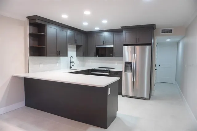 a kitchen with kitchen island a refrigerator and a sink