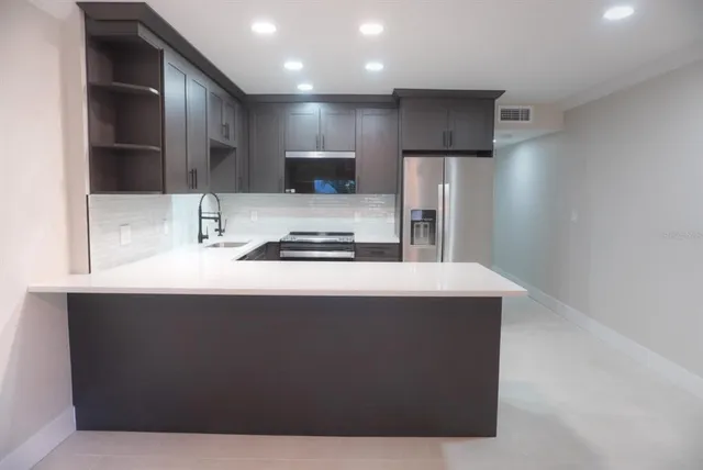 a kitchen with kitchen island stainless steel appliances a sink and refrigerator