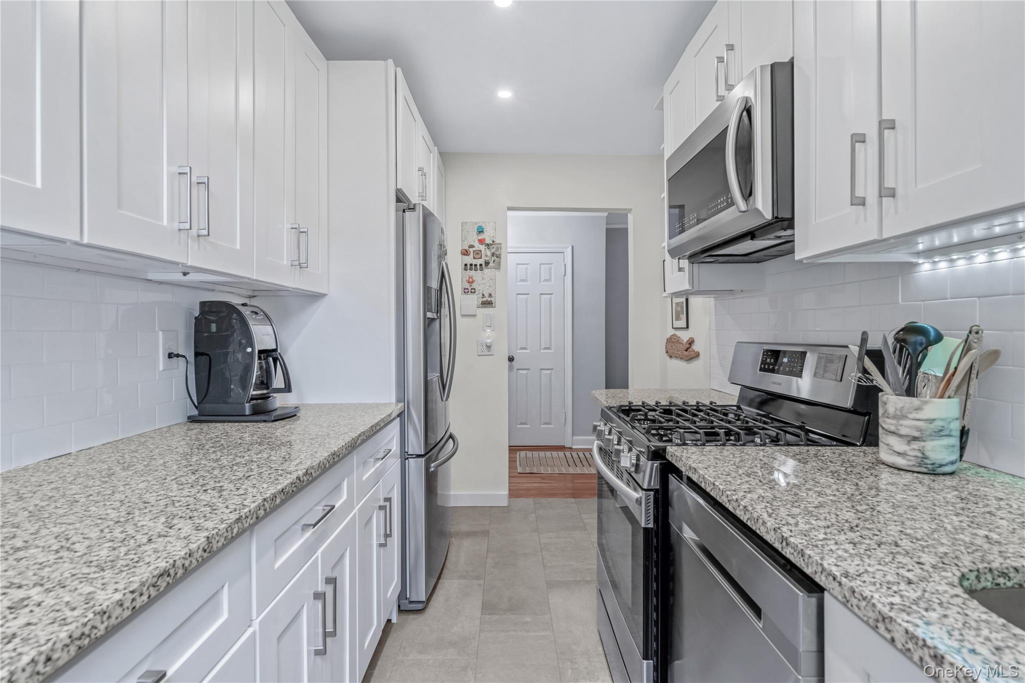 90 Knightsbridge Road, Unit 3N Great Neck, NY 11021 - Photo 9 of 16 a kitchen with stainless steel appliances granite countertop a sink stove and refrigerator