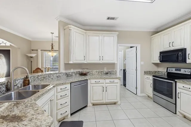 a kitchen with granite countertop a sink stainless steel appliances and white cabinets