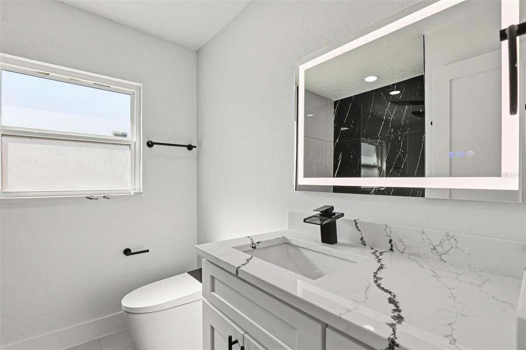 3216 West Beach Street Tampa, FL 33607 - Photo 21 of 63 a bathroom with a sink a toilet and mirror
