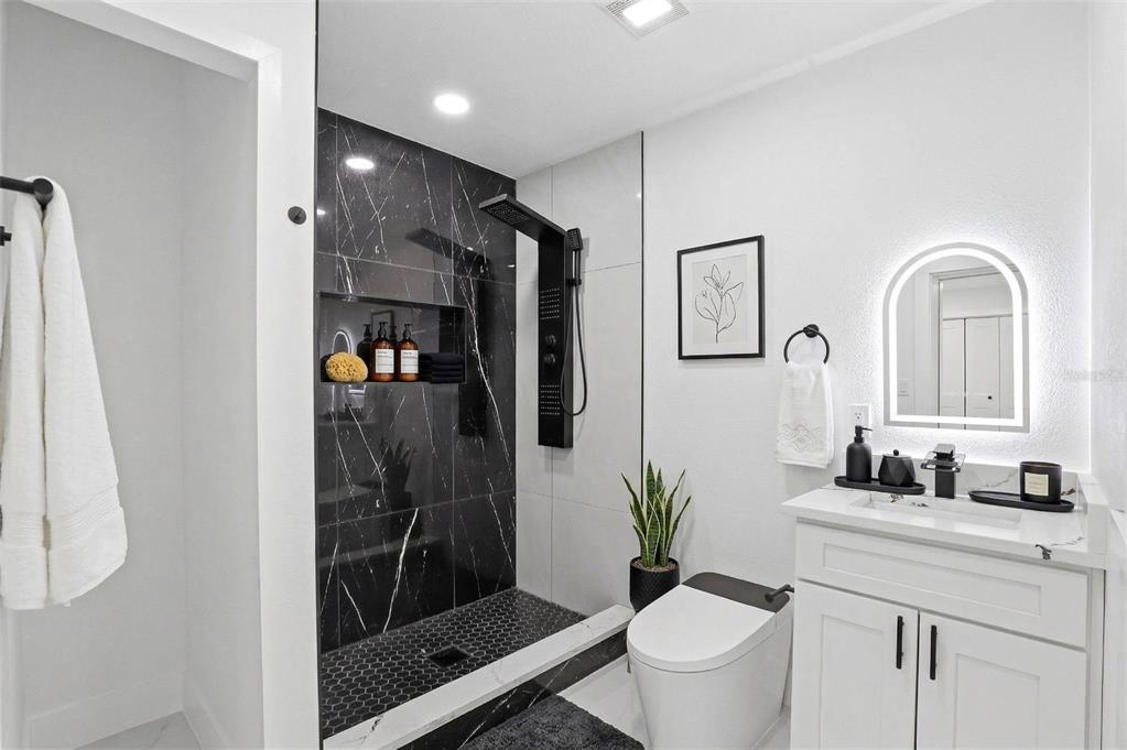 3216 West Beach Street Tampa, FL 33607 - Photo 29 of 63 a bathroom with a granite countertop sink a toilet a mirror and shower