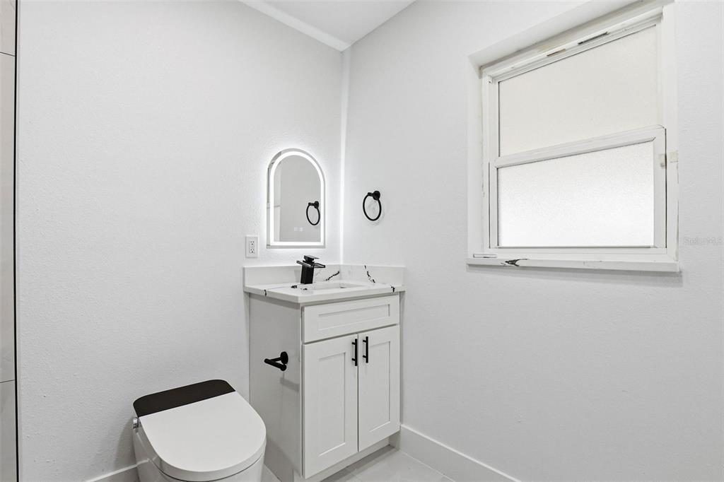 3216 West Beach Street Tampa, FL 33607 - Photo 32 of 63 a bathroom with a toilet a sink a vanity and mirror