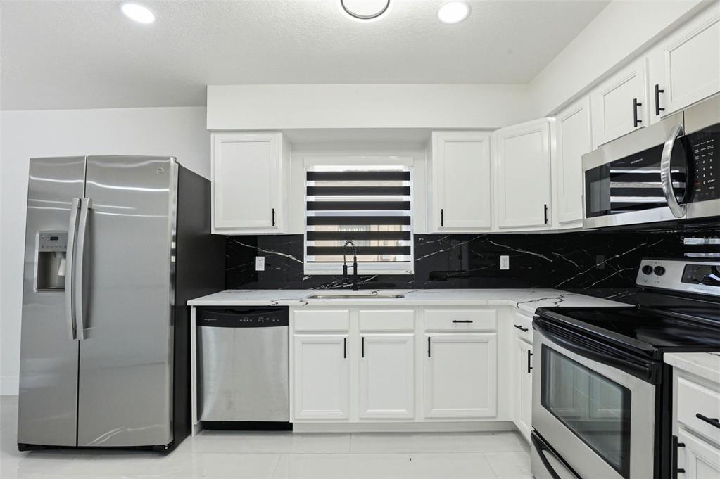 3216 West Beach Street Tampa, FL 33607 - Photo 41 of 63 a kitchen with white cabinets and stainless steel appliances