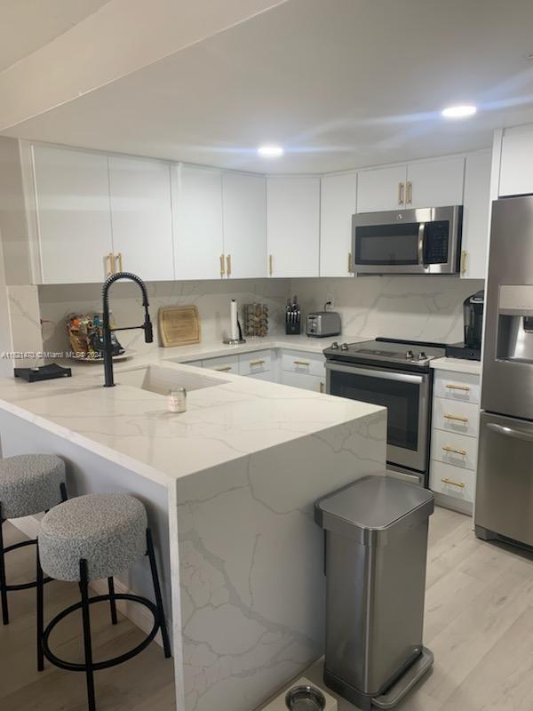 4590 Southwest 68th Ct Circle, Unit 4 Miami, FL 33155 - Photo 4 of 32 a kitchen with stainless steel appliances a sink a stove a refrigerator cabinets a dining table and chairs