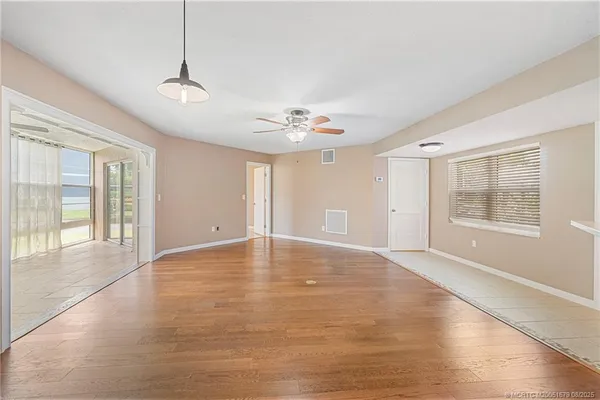a view of an empty room with a window and wooden floor