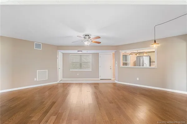 a view of an empty room with wooden floor and a window