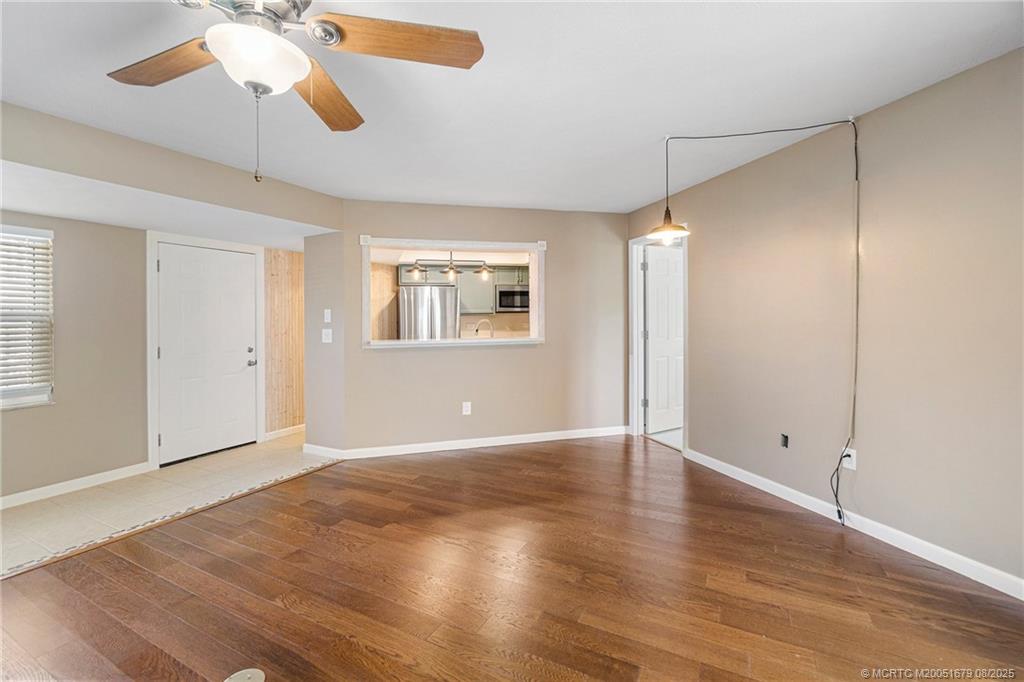 3218 Southeast Aster Lane, Unit P116 Stuart, FL 34994 - Photo 36 of 45 an empty room with wooden floor chandelier fan and windows