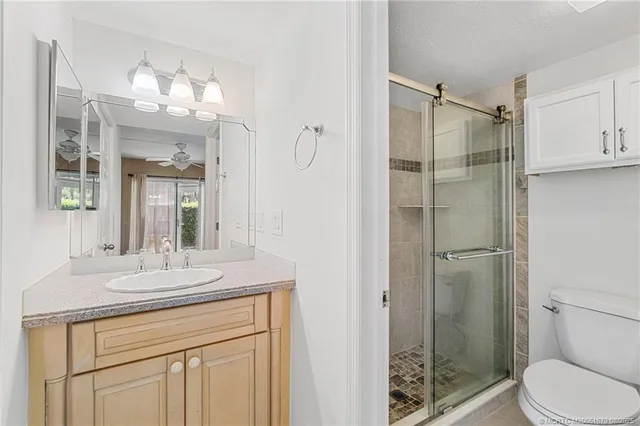 a bathroom with a granite countertop shower sink vanity and mirror