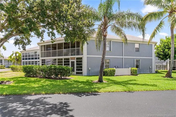 a view of a house with a yard and palm trees