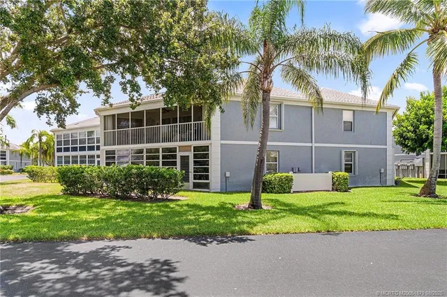 a view of a house with a yard and palm trees