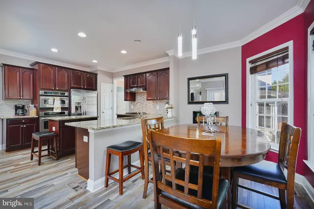 a kitchen with stainless steel appliances granite countertop a stove top oven a sink dishwasher a dining table and chairs with wooden floor