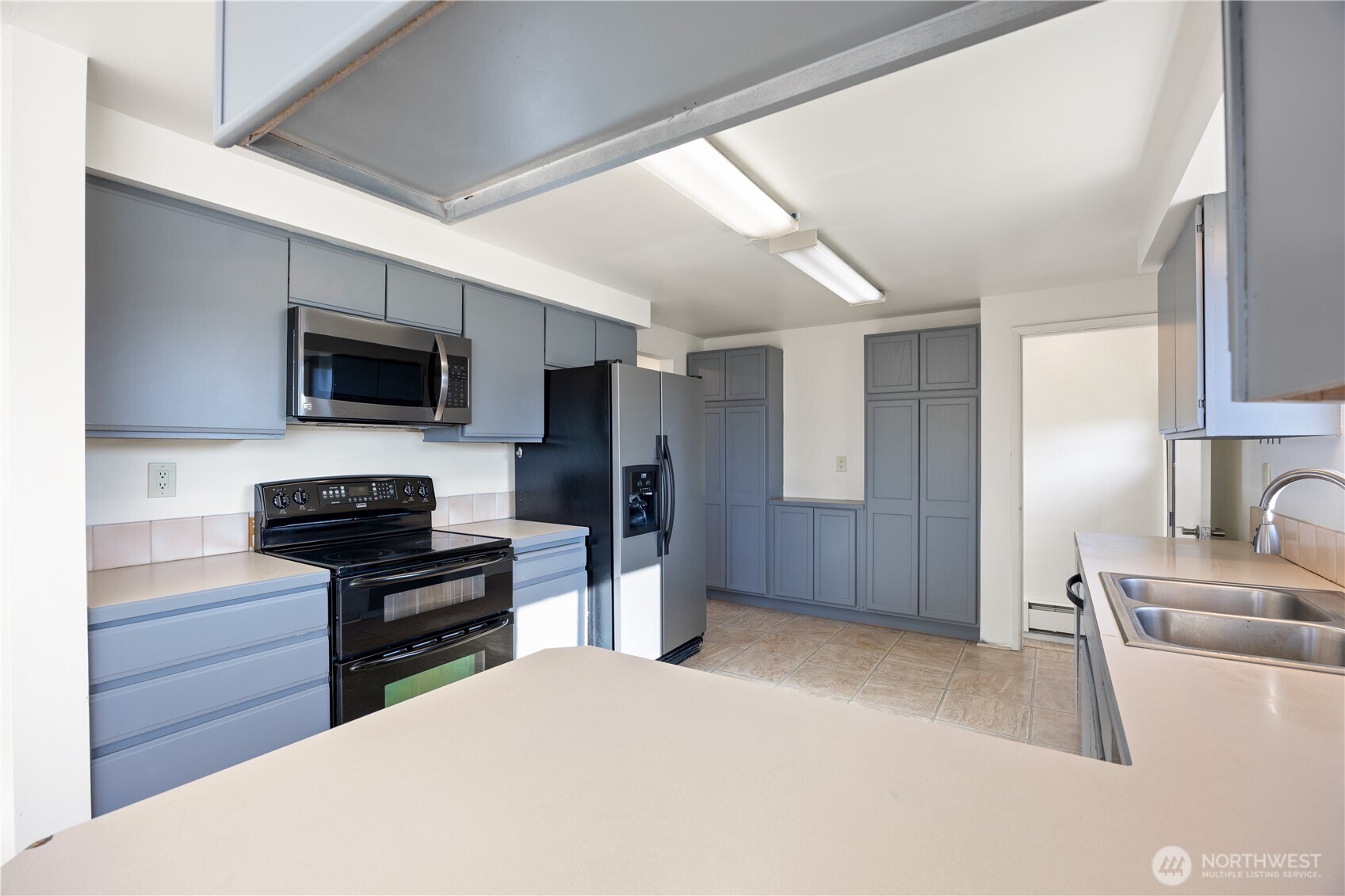 110 Linden Avenue Moses Lake, WA 98837 - Photo 12 of 40 a kitchen with stainless steel appliances kitchen island granite countertop a refrigerator and a stove top oven