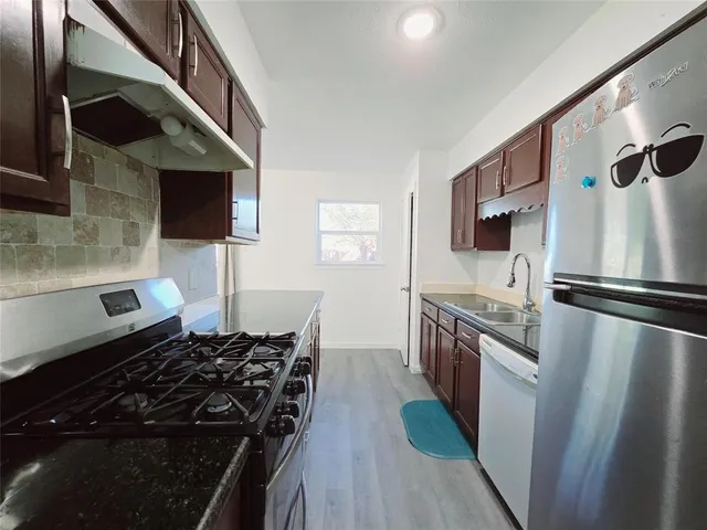 a kitchen with stainless steel appliances granite countertop a stove a sink and a refrigerator