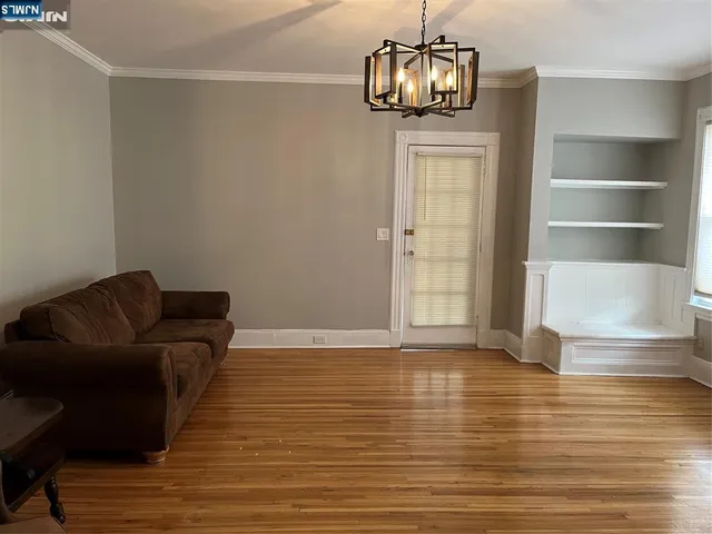 an empty room with wooden floor cabinet and windows