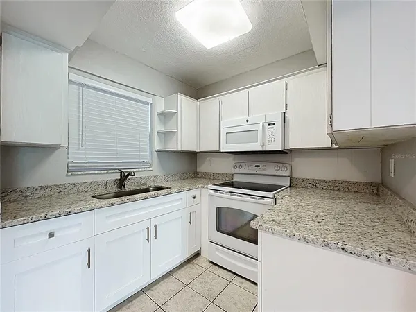 a kitchen with granite countertop white cabinets and white appliances