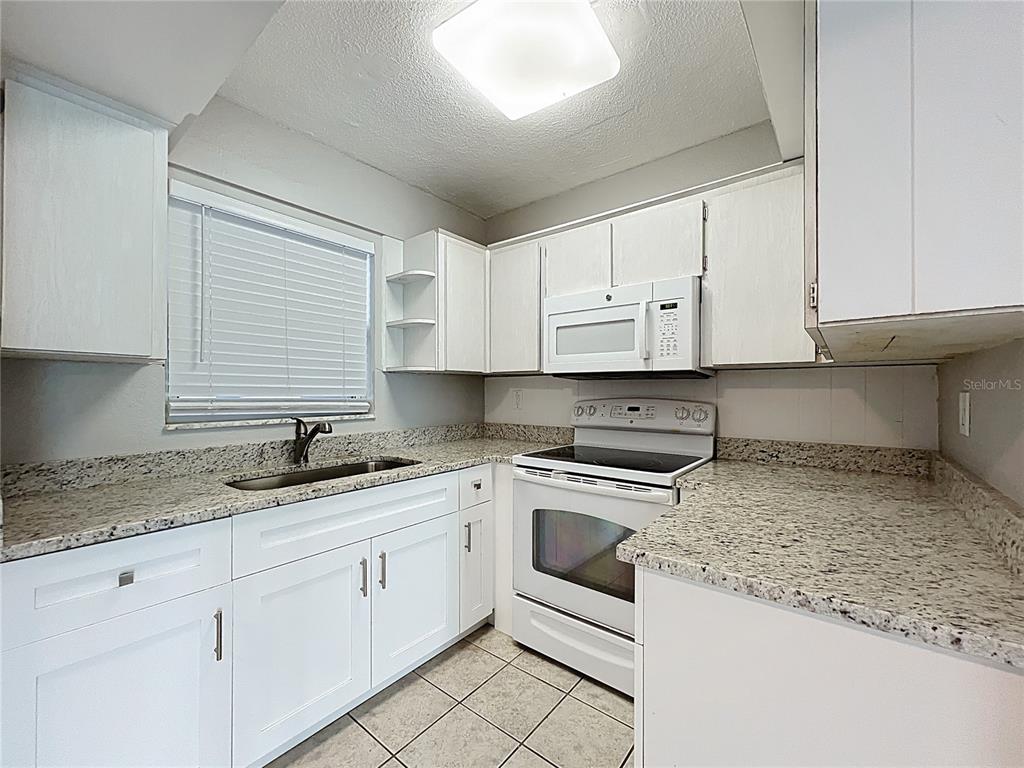 11705 3rd Street East, Unit 4 Treasure Island, FL 33706 - Photo 8 of 23 a kitchen with granite countertop white cabinets and white appliances