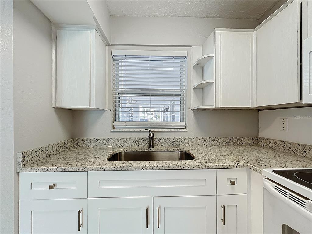 11705 3rd Street East, Unit 4 Treasure Island, FL 33706 - Photo 9 of 23 a kitchen with granite countertop white cabinets sink and window
