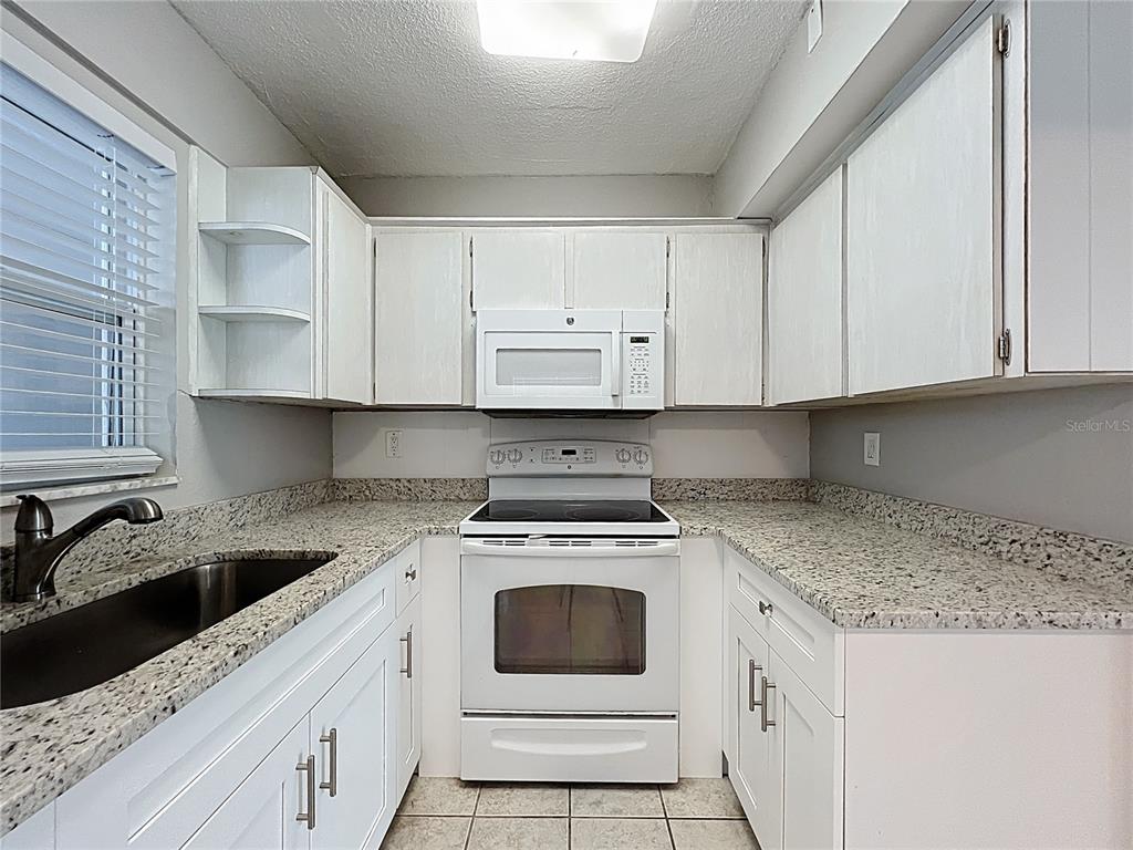 11705 3rd Street East, Unit 4 Treasure Island, FL 33706 - Photo 10 of 23 a kitchen with granite countertop white cabinets and white appliances