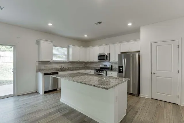 a kitchen with stainless steel appliances granite countertop a refrigerator a stove a sink and a microwave