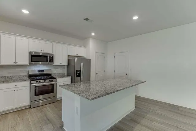 a kitchen with stainless steel appliances granite countertop a stove a sink and a refrigerator