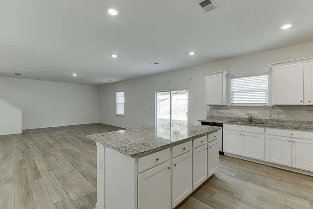 a kitchen with granite countertop sink stove and cabinets