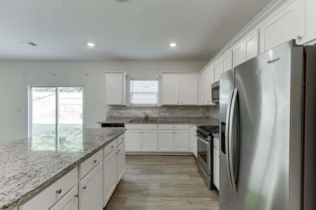 a kitchen with stainless steel appliances granite countertop a refrigerator and a sink
