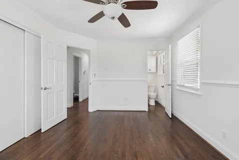 an empty room with wooden floor cabinet and windows