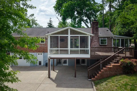 a view of a house with wooden deck and a tree
