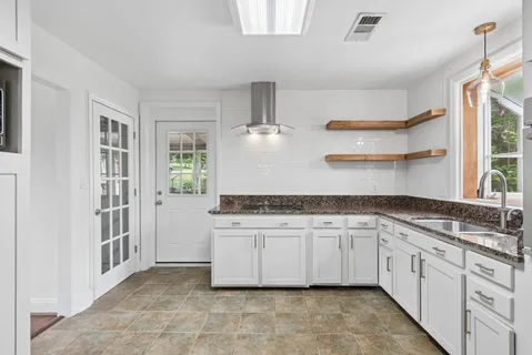 a kitchen with granite countertop a sink stove and cabinets