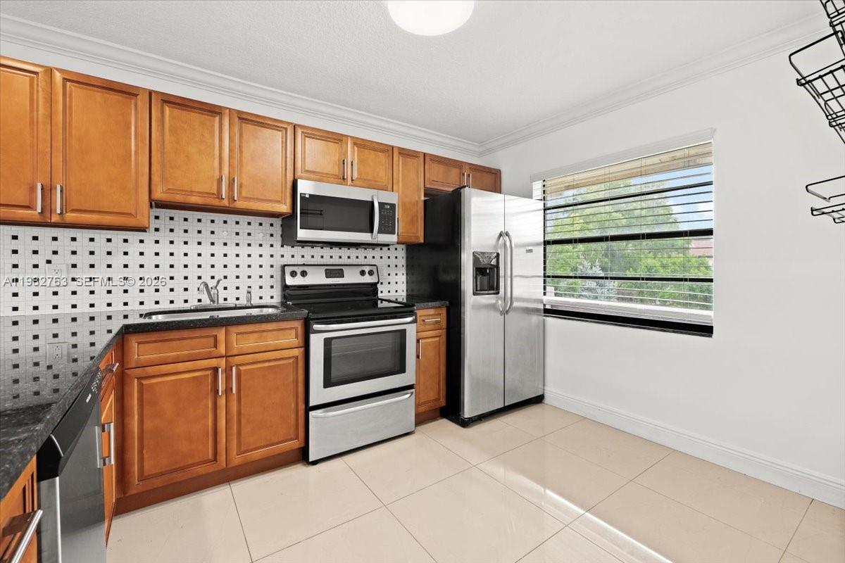 7944 Eastlake Drive, Unit D Boca Raton, FL 33433 - Photo 7 of 29 a kitchen with stainless steel appliances kitchen island granite countertop a stove a sink and a microwave