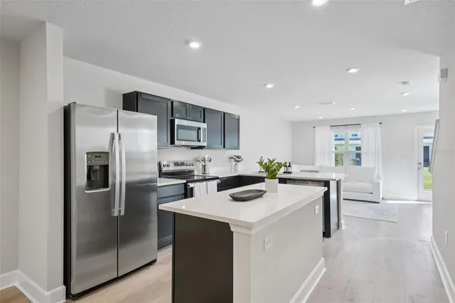 a kitchen with a refrigerator a microwave oven a sink and chairs