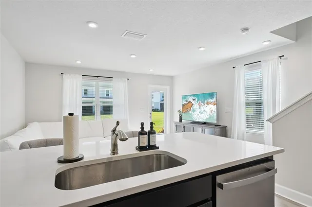 a kitchen with a sink a counter top space and living room view