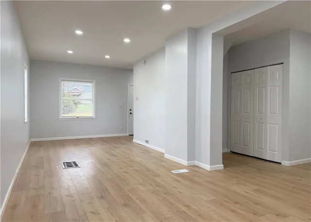 a view of empty room with wooden floor and window