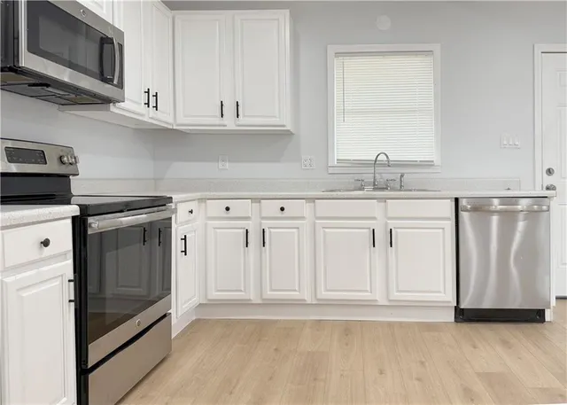 a kitchen with white cabinets stainless steel appliances and sink