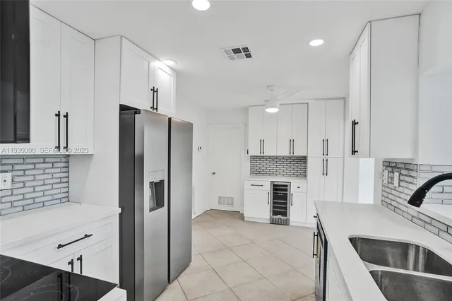 a kitchen with stainless steel appliances granite countertop a refrigerator a stove and a sink