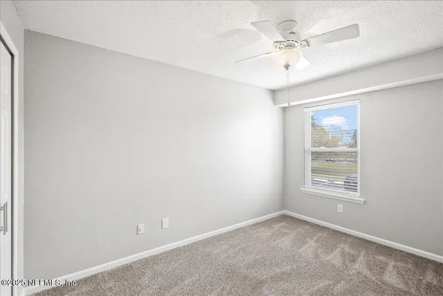 an empty room with windows and ceiling fan