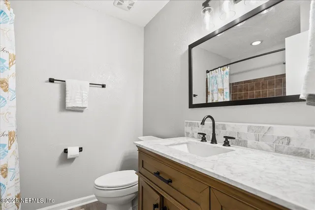 a bathroom with a granite countertop sink a large mirror and toilet