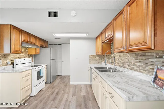 a kitchen with a sink cabinets stainless steel appliances and a large window