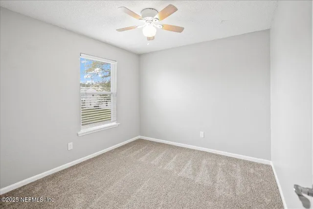 an empty room with a window and a fan