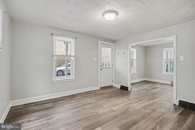 an empty room with wooden floor and windows