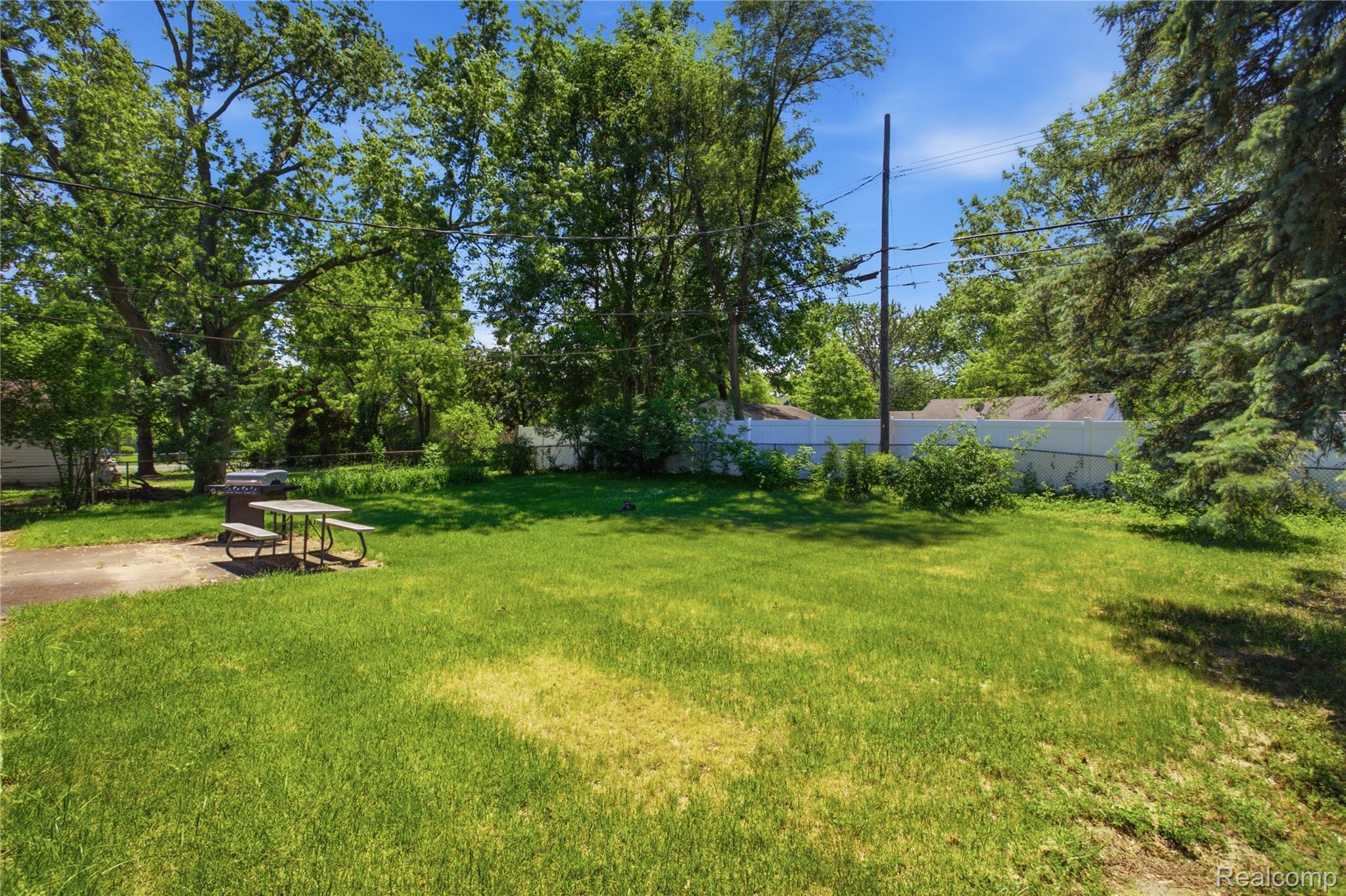 47395 Dequindre Road Rochester, MI 48307 - Photo 14 of 19 Expansive green lawn with mature trees and a white privacy fence