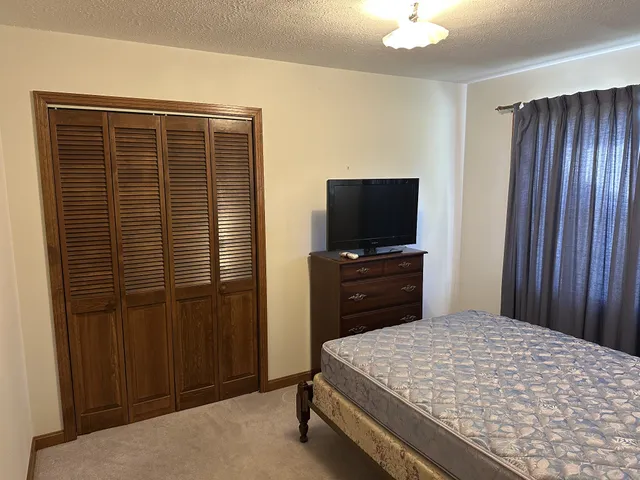 a bedroom with a bed and a flat tv screen on dresser