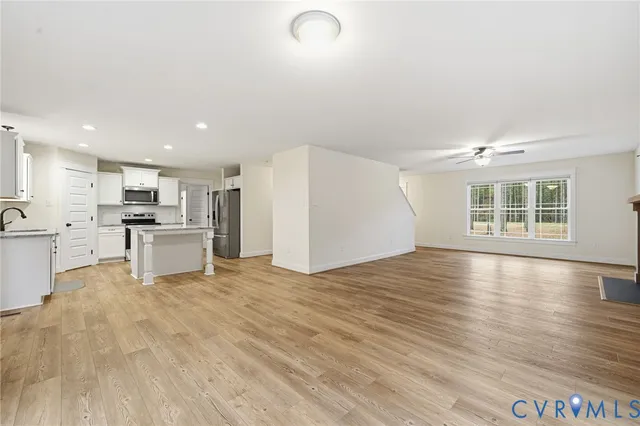 a view of an empty room with kitchen and window