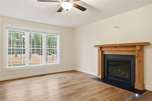 a view of an empty room with wooden floor fireplace and a window