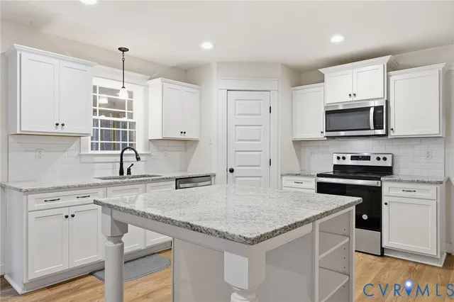 a kitchen with granite countertop a stove sink and microwave
