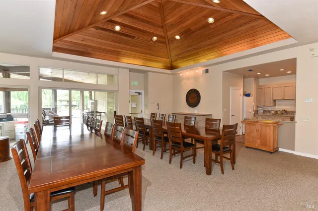 a dining hall with stainless steel appliances a dining table and chairs with the floor to ceiling window