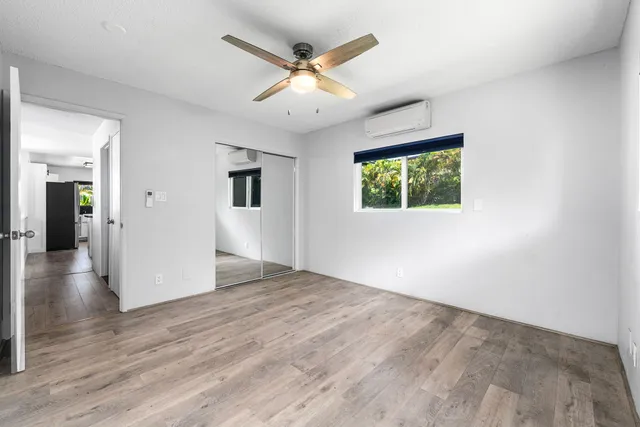 an empty room with wooden floor chandelier and windows
